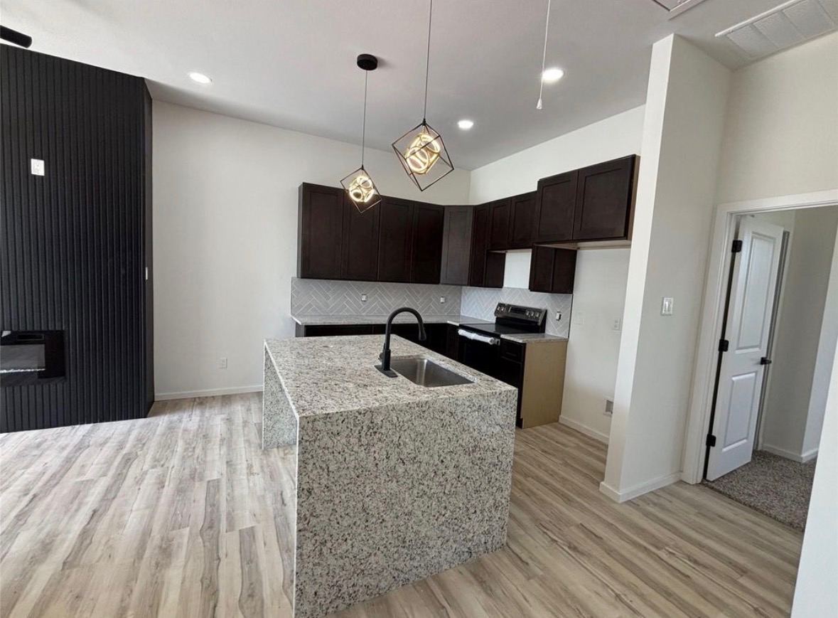 Kitchen with dark brown cabinetry and granite island