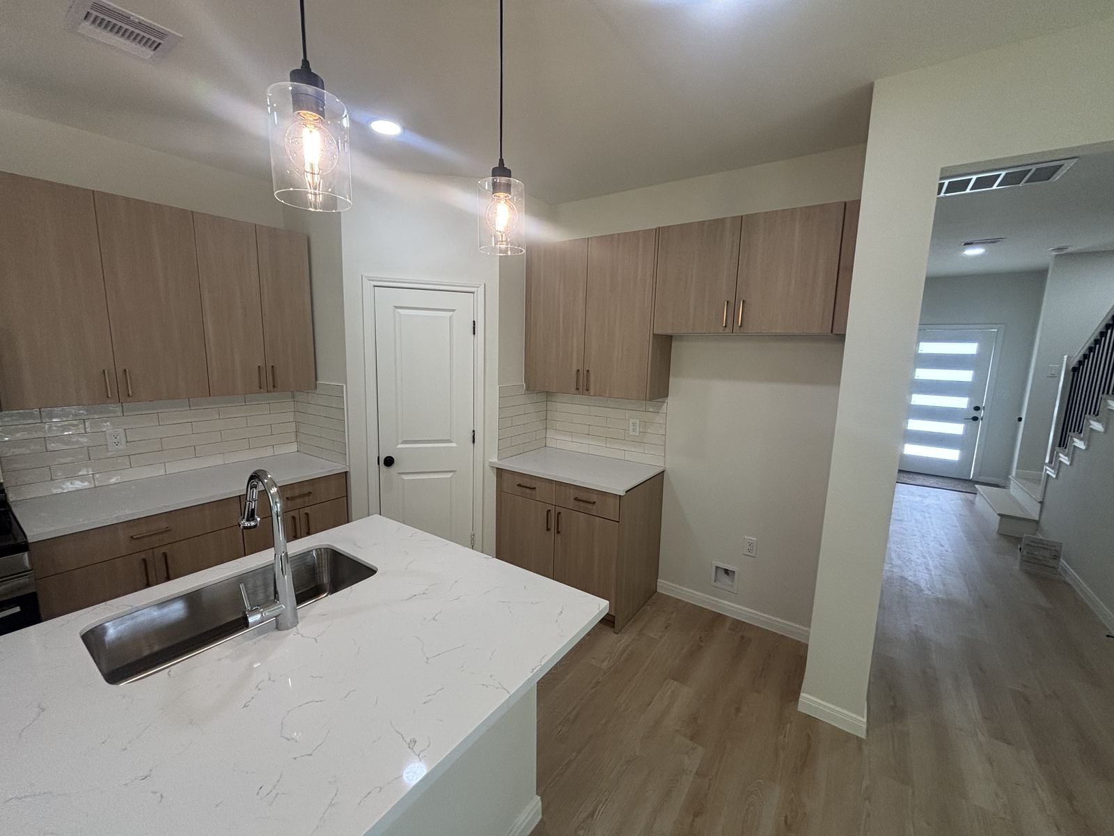 Light wood kitchen cabinetry near entry hallway