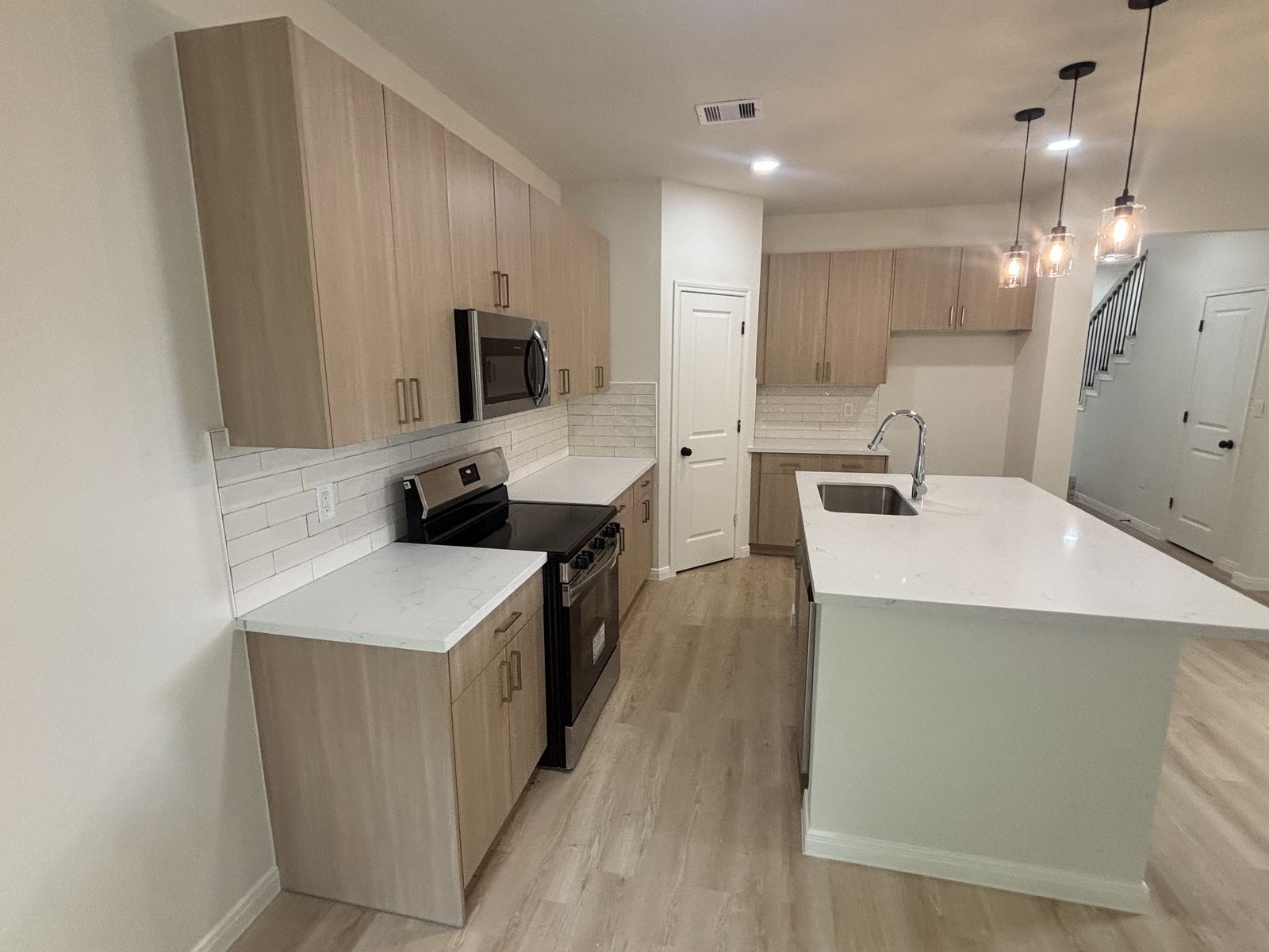 Light wood galley kitchen with quartz countertops and island